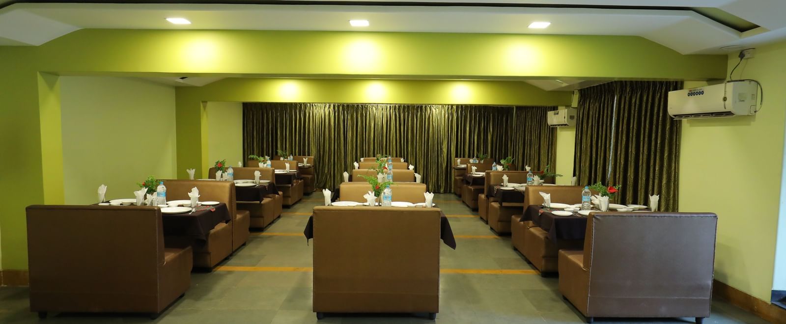 Wide view of the dining area at Krushnai Resort with several seating arrangements and yellow lighting.