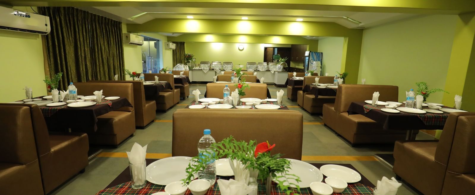 Close-up of tables set with plates and bottles on a carpeted floor at Krushnai Resort.