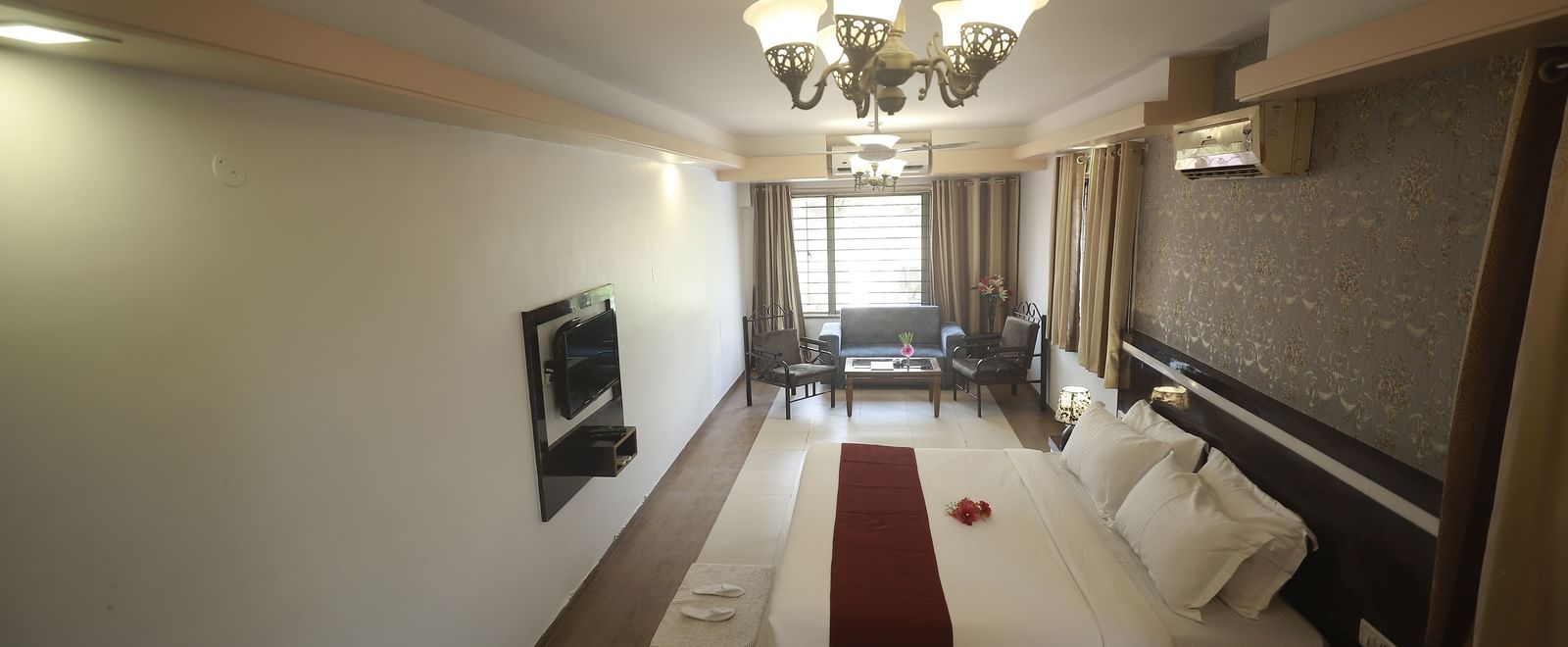 Side view of the Deluxe Room at Mountview Resort, which features a king size bed, a bedside table, wall-mounted TV, and curtains drawn.