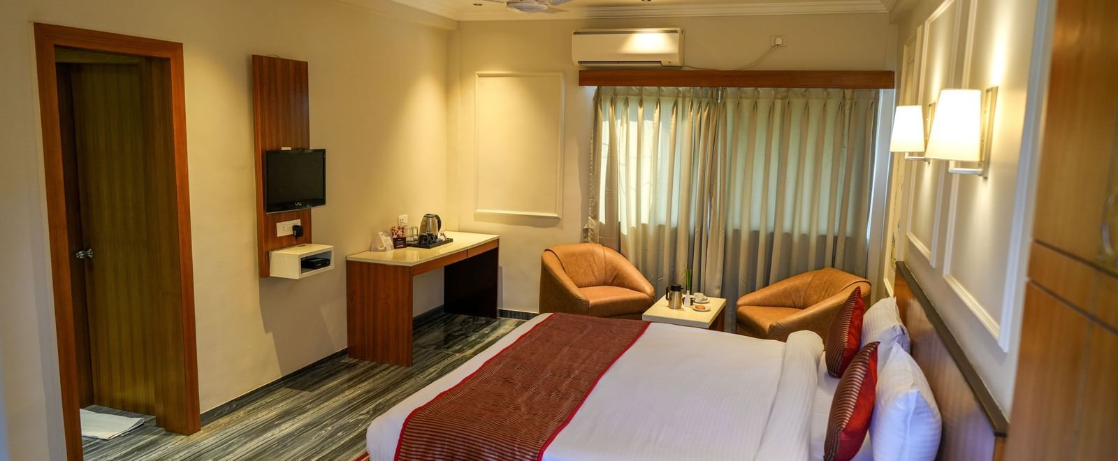 Well-appointed guest room with a king-size bed and seating for relaxation at Pravasa Hotel Kolhapur.
