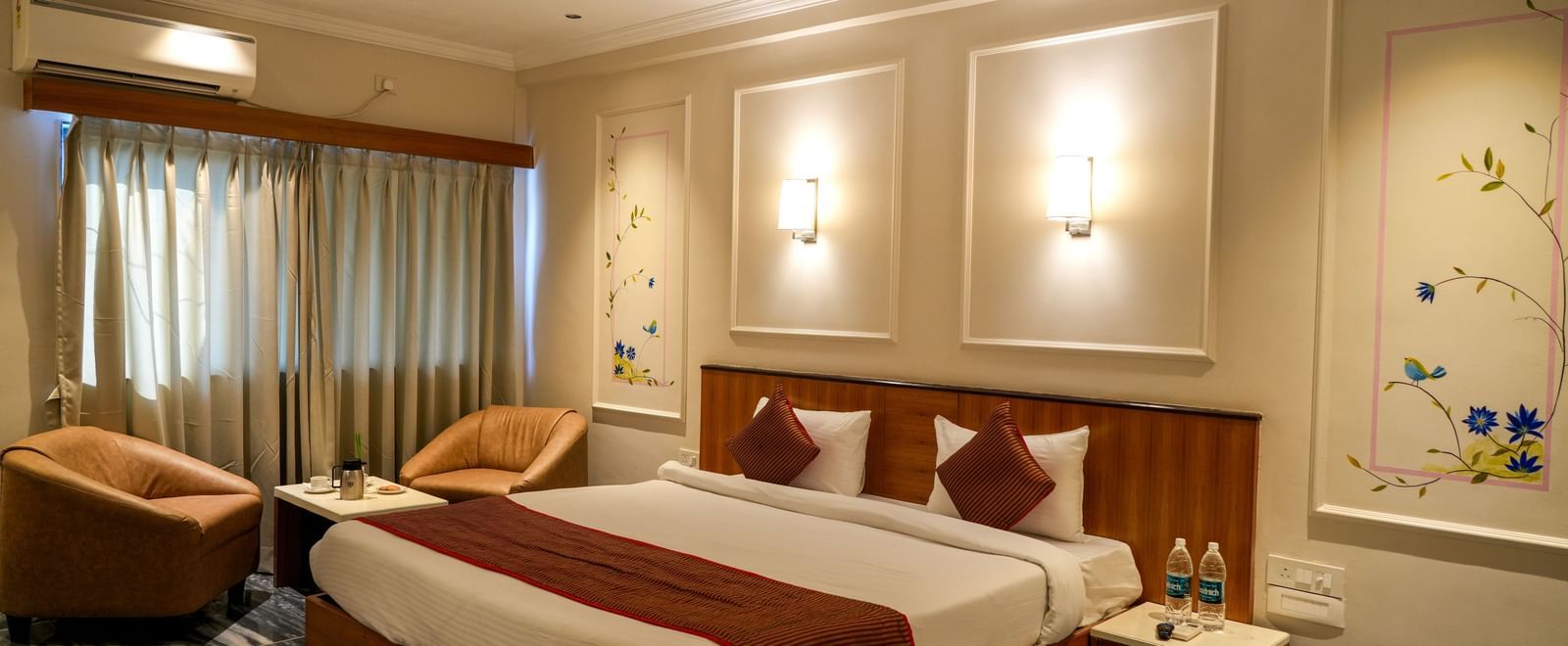 Stylish guest room with a double bed, seating area, and soft lighting at Pravasa Hotel Kolhapur.