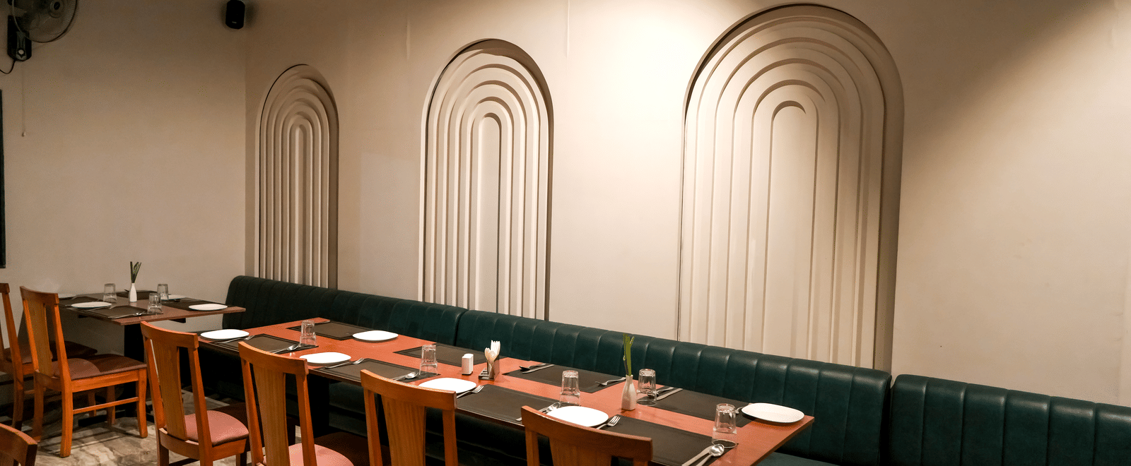  A comfortable dining booth with a dark green leather seat and decorative recessed white archways at Pravasa Hotel, Kolhapur. 