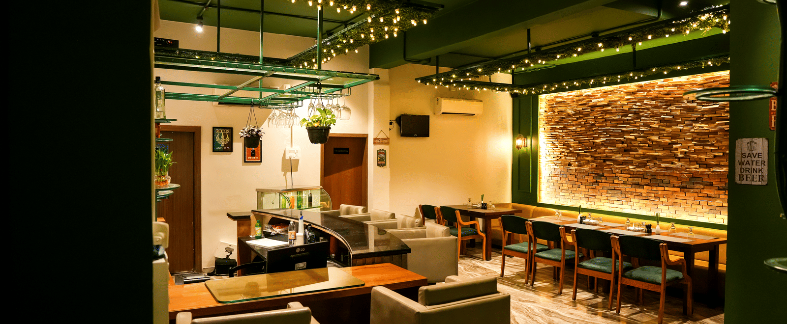  An overall view of the lounge and dining space with modern armchairs and a backlit brick feature wall at Pravasa Hotel, Kolhapur.