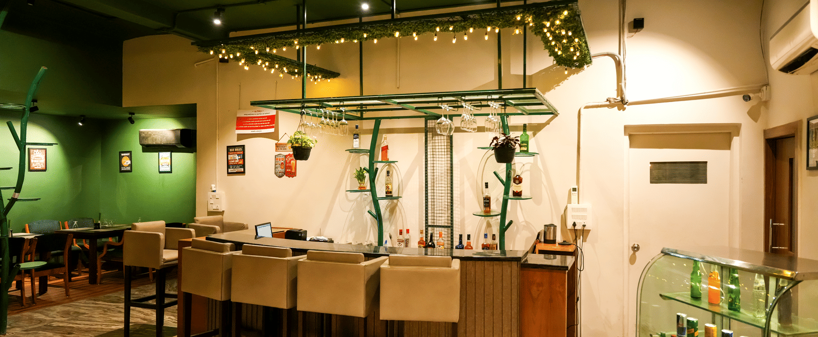  A well-lit service bar with high stools and a glass display case for drinks in the casual dining area of Pravasa Hotel, Kolhapur.