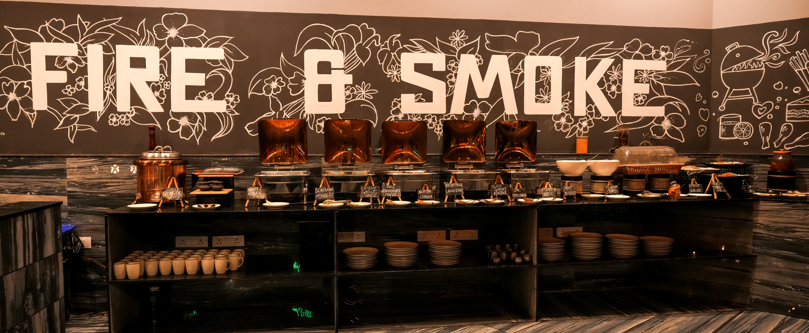 Restaurant buffet counter with “Fire & Smoke” sign at Pravasa Hotel, Kolhapur.