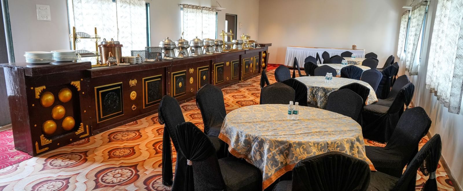 Banquet hall with round tables and elegant seating for gatherings at Pravasa Hotel Kolhapur.