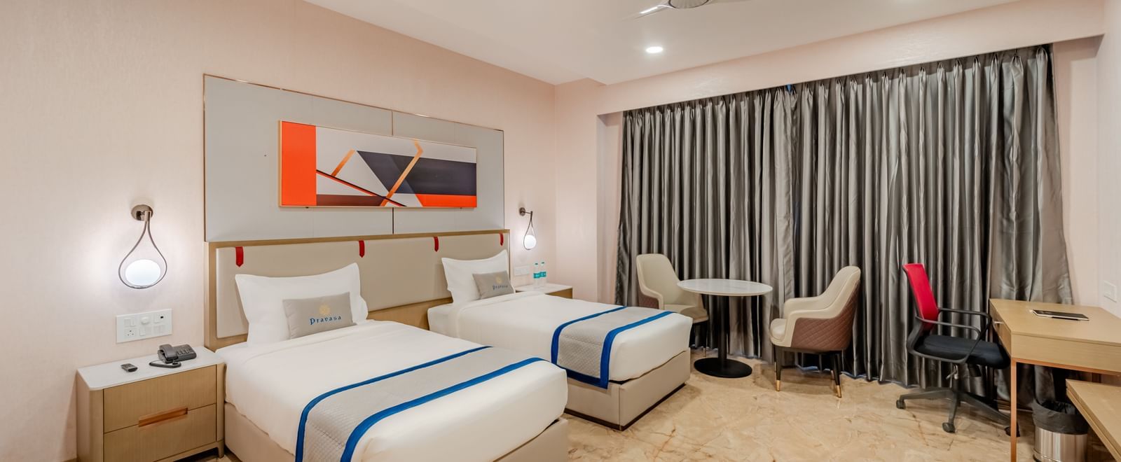 A hotel room with twin beds, a desk, and modern decor | Superior Room | Pravasa Hotel, Vijayapura