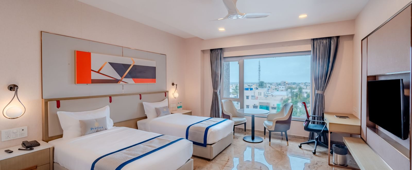 Hotel room with twin beds, a large window, and city view | Superior Room | Pravasa Hotel, Vijayapura