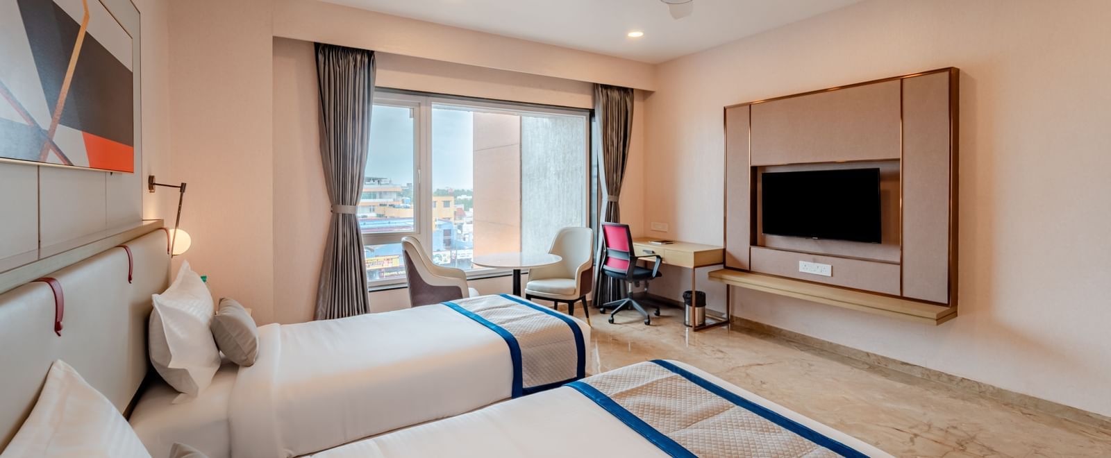Hotel room with twin beds, a large window, and city view | Superior Room | Pravasa Hotel, Vijayapura