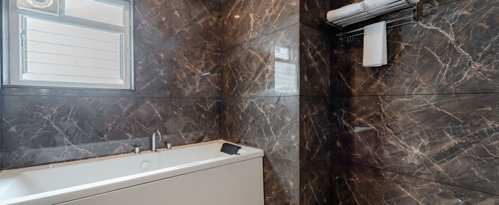 Modern bathroom with a bathtub, shower, and contemporary fixtures | Studio Suite | Pravasa Hotel, Vijayapura