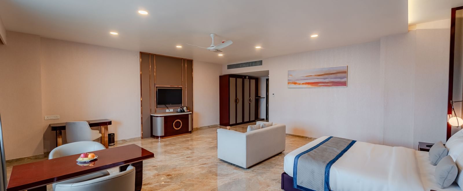 Luxury suite bedroom with a large bed, sofa, and dining area | Suite | Pravasa Hotel, Vijayapura