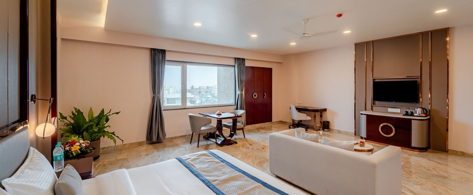 Spacious suite featuring a comfortable bed, lounge area, and city views | Suite | Pravasa Hotel, Vijayapura