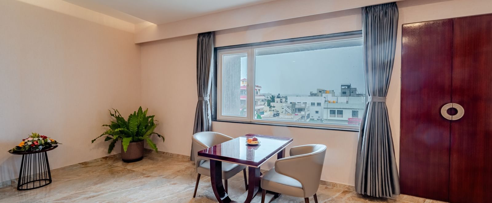 Expansive suite offering a large bed, seating, and a view of the outside | Suite | Pravasa Hotel, Vijayapura