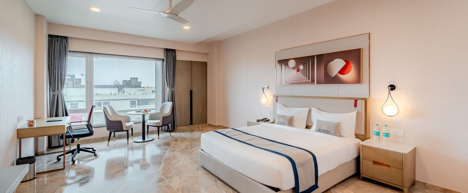 Spacious hotel room featuring a king-size bed, work desk, and city views | Premium Room | Pravasa Hotel, Vijayapura