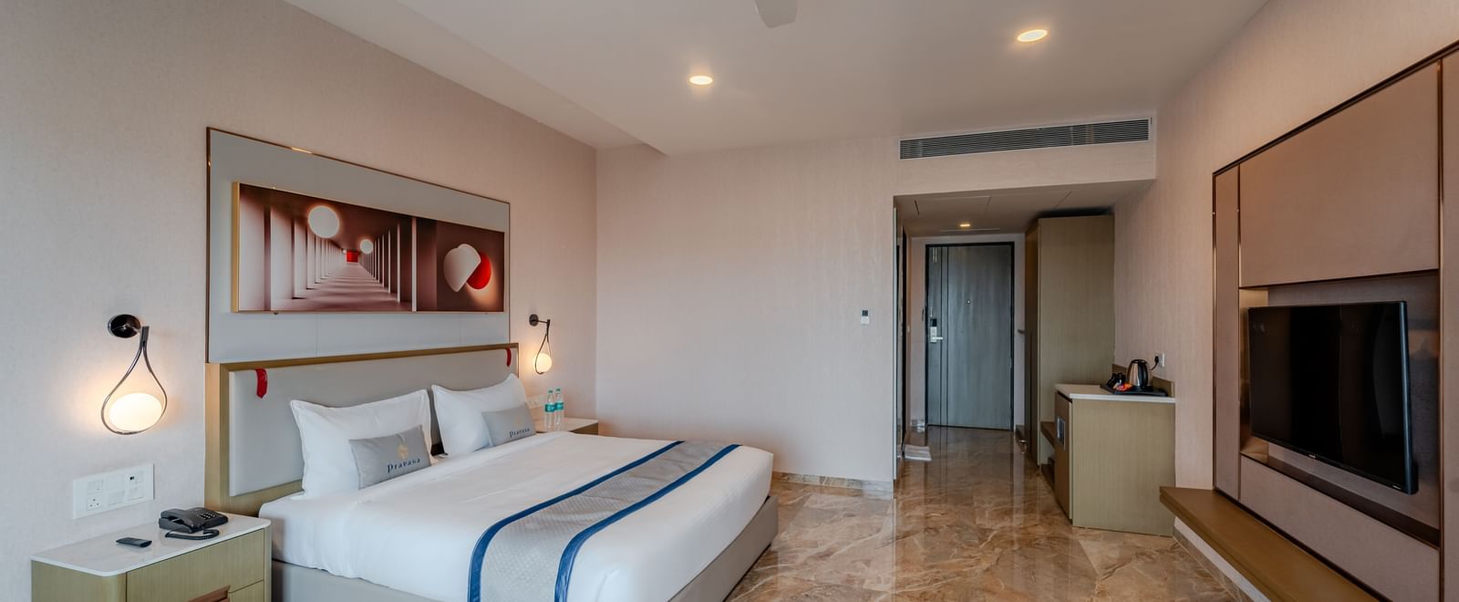 Hotel bedroom featuring a king bed, bedside tables, and a large window | Premium Room | Pravasa Hotel, Vijayapura