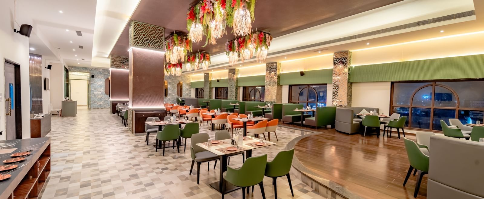 The restaurant with orange and green seating and intricate ceiling decorations | Pravasa Hotel, Vijayapura