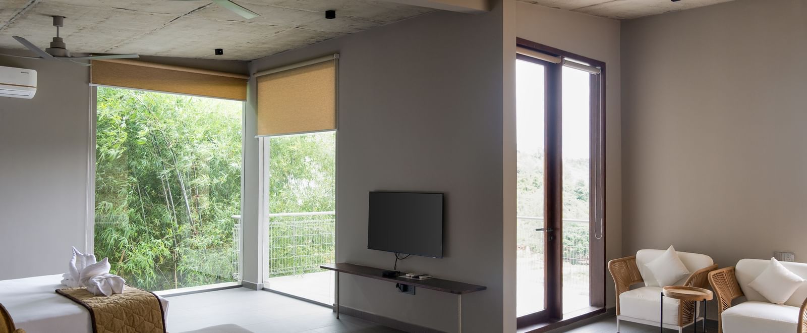 A spacious living area with a large window, a television, a coffee table, and multiple seating options | Gaia Studio | RD's Nature Retreat, Bangalore