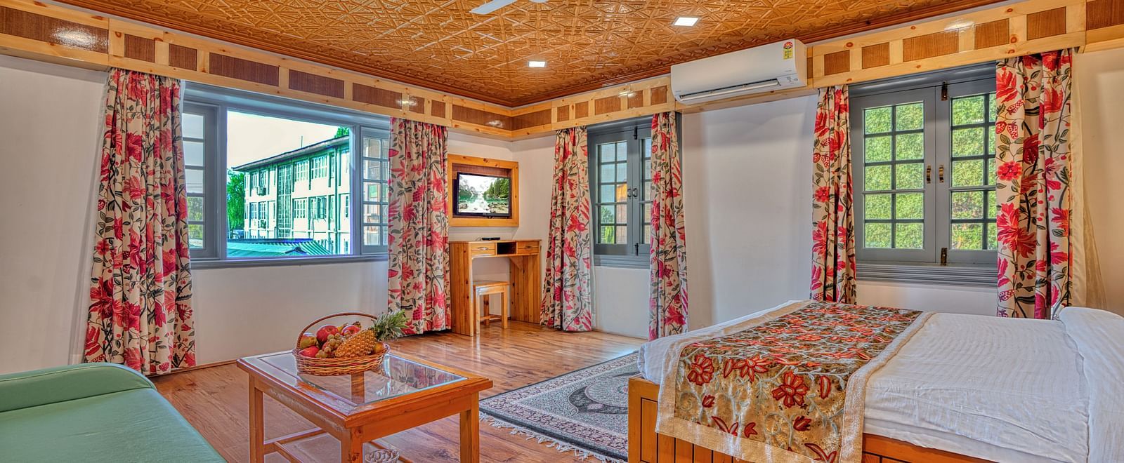 Elegant guest room with wooden accents and floral curtains at Royal Comfort Regency, perfect for a peaceful stay.