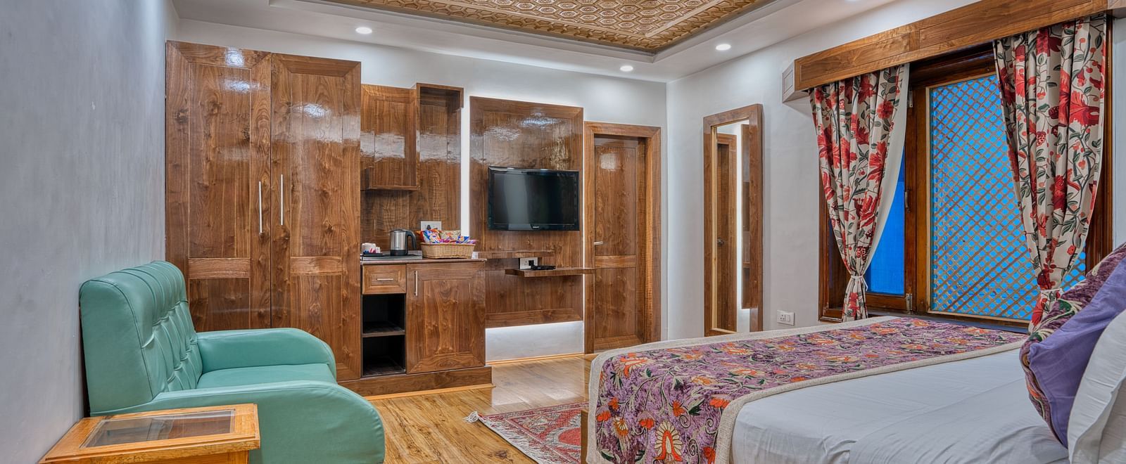 Spacious bedroom at Royal Comfort Regency with elegant furnishings, wooden accents and soft lighting for a restful and refined stay.