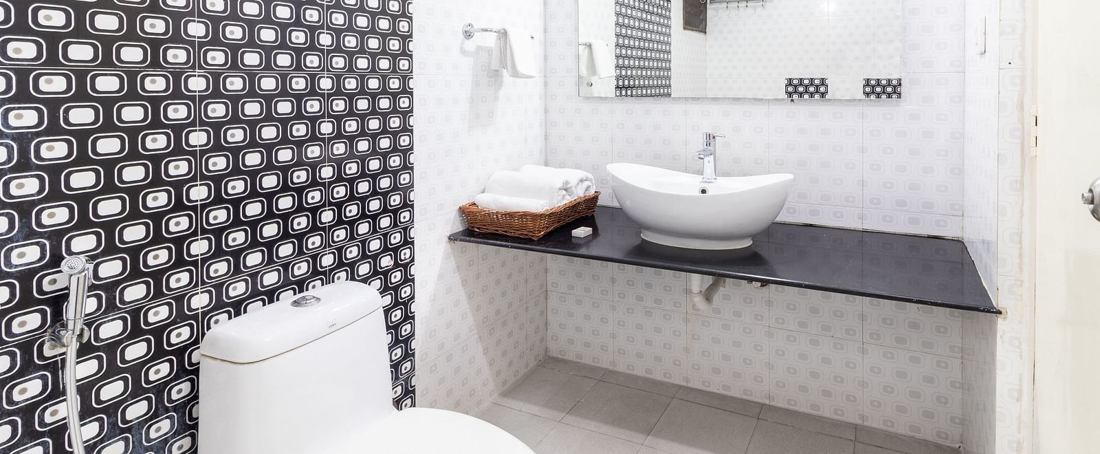 A bathroom featuring a toilet, a sink, and toiletries placed on the counter-top at Sanctum Suites Domlur, Bangalore.