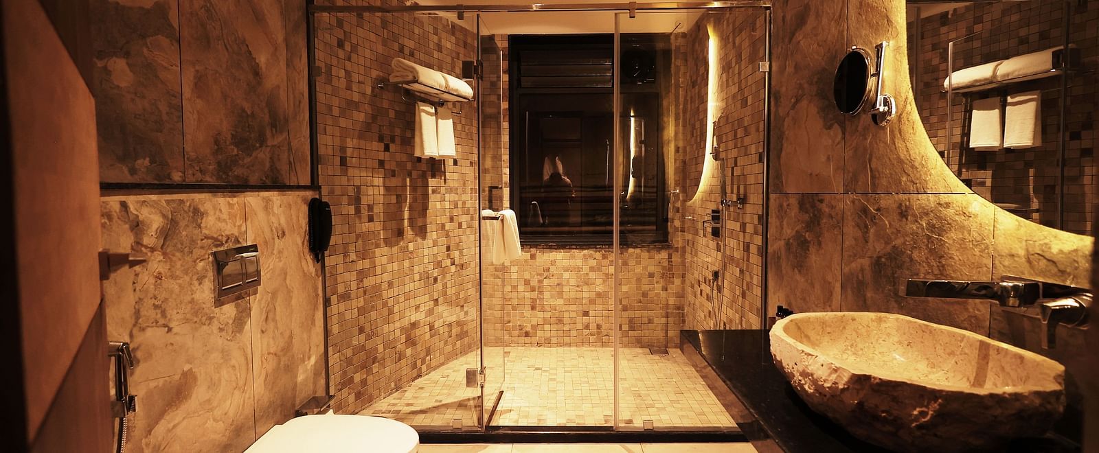 A bathroom of Luxury Villa with Plunge Pool showcasing unique fixtures, stone walls, and warm lighting at The Qualia Resort Club & Brewery, Udaipur.