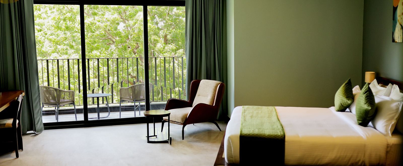 Club Suite with Valley View Sitout with a king size bed, a chair, and a balcony overlooking greenery.