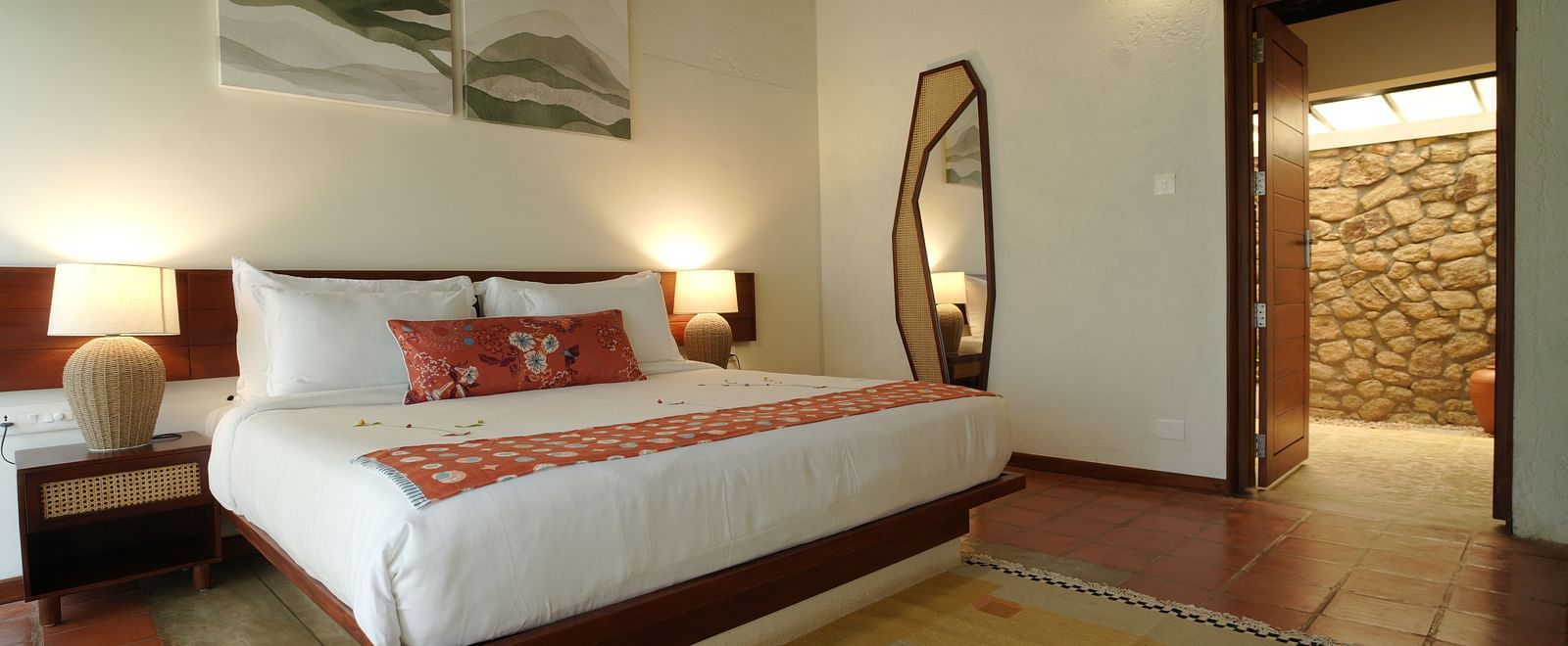  A well-appointed bedroom at Vaasta Vagamon featuring a large bed, bedside tables with lamps, a floor-length mirror, and artwork.