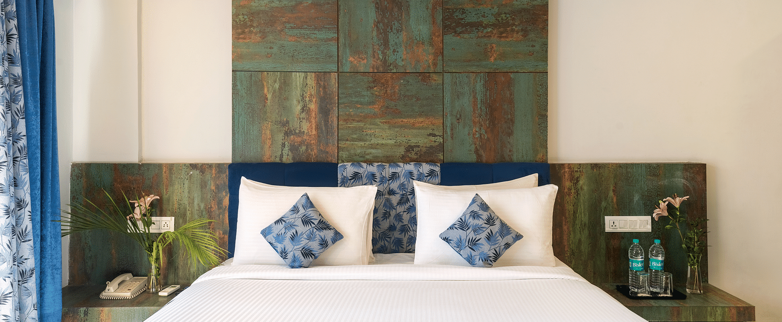 A bedroom with a made bed, decorative pillows, and artwork on the wall - Via Lakhela Resort & Spa