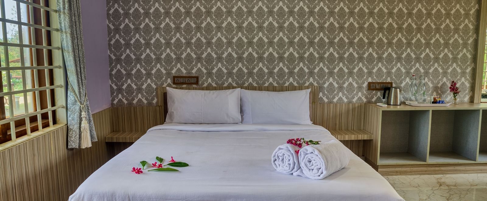  A bedroom with a large white bed against a textured, light-coloured wall, with a small bedside table, ready for guests. - Vintage Trails by Ilara