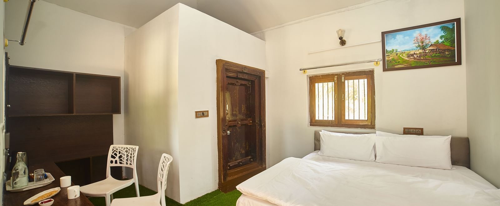 The interior of a white, modern, capsule-style accommodation unit with a large circular bed, a round green rug, and a small built-in desk or shelf. - Vintage Trails by Ilara