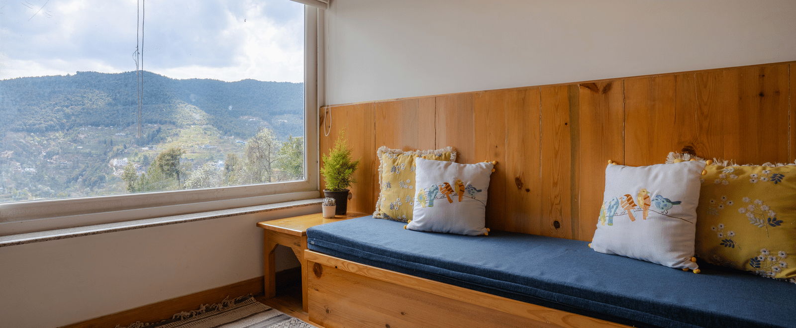 A room at Ziran Retreat with a sofa that doubles as a daybed, located in front of a wide window showing a mountain view.