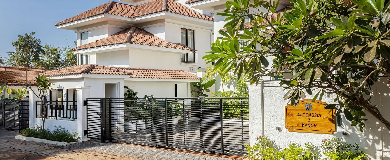 A side view of a modern villa with a landscaped garden, gated entrance, and stylish design elements - BluSalzz Villas - Alocassia, Anjuna