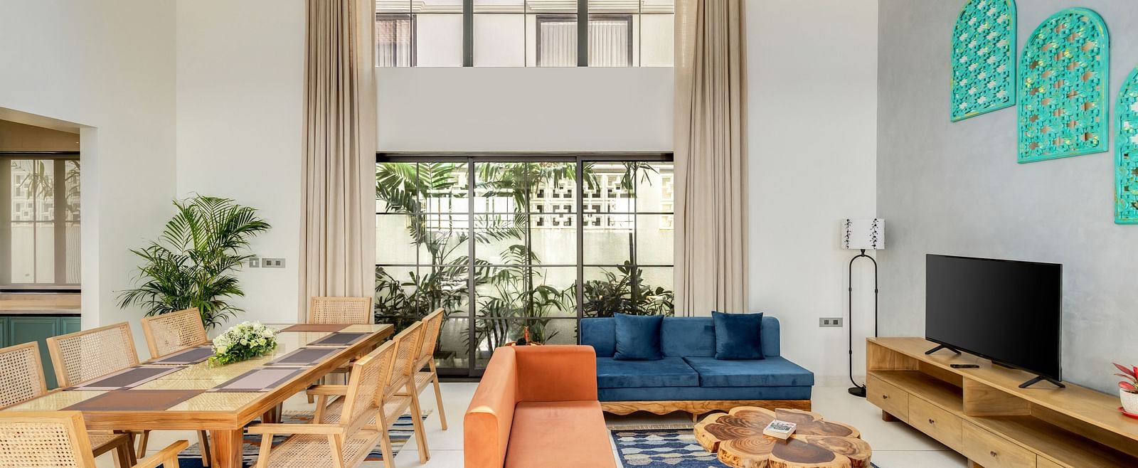 A spacious living and dining room with high ceilings, contemporary furnishings, and large windows flooding the space with natural light - BluSalzz Villas - Alocassia, Anjuna