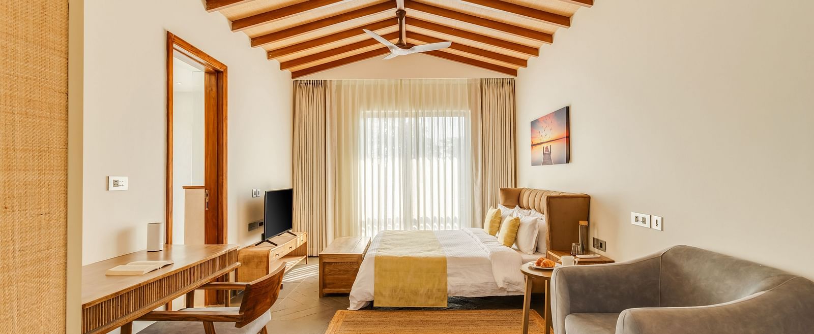 A spacious bedroom with a pitched wooden ceiling, a comfortable bed, seating area, and a bright, airy ambience - BluSalzz Villas - Alocassia, Anjuna