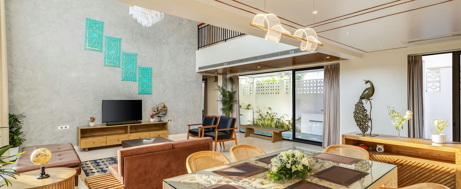 A bright and modern dining area with a large wooden table, contemporary chairs, and an open-plan kitchen in the background - BluSalzz Villas - Alocassia, Anjuna