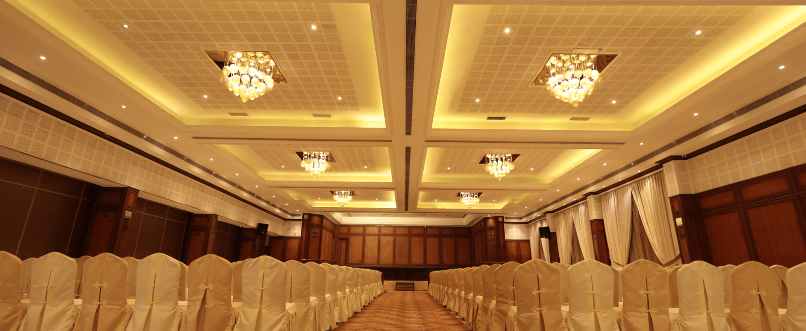 A front view of a banquet hall with chairs arranged on both sides with yellow lighting | Cenneys Gateway