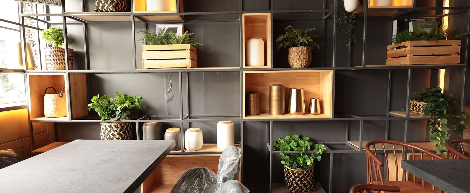 A spacious dining area with a background shelf decorated with plants, pots, and vessels | Cenneys Gateway