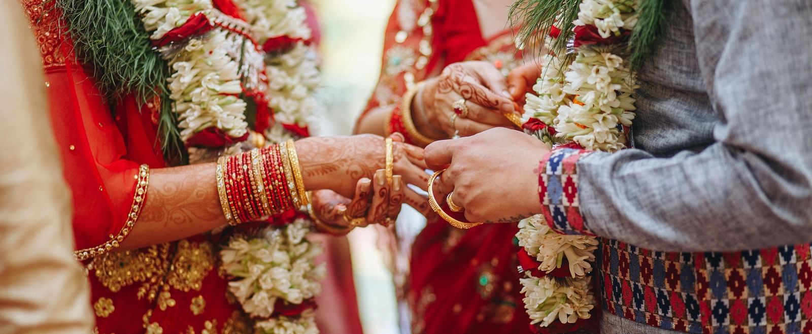 a couple wearing flower garlands exchanging rings during the wedding ceremony