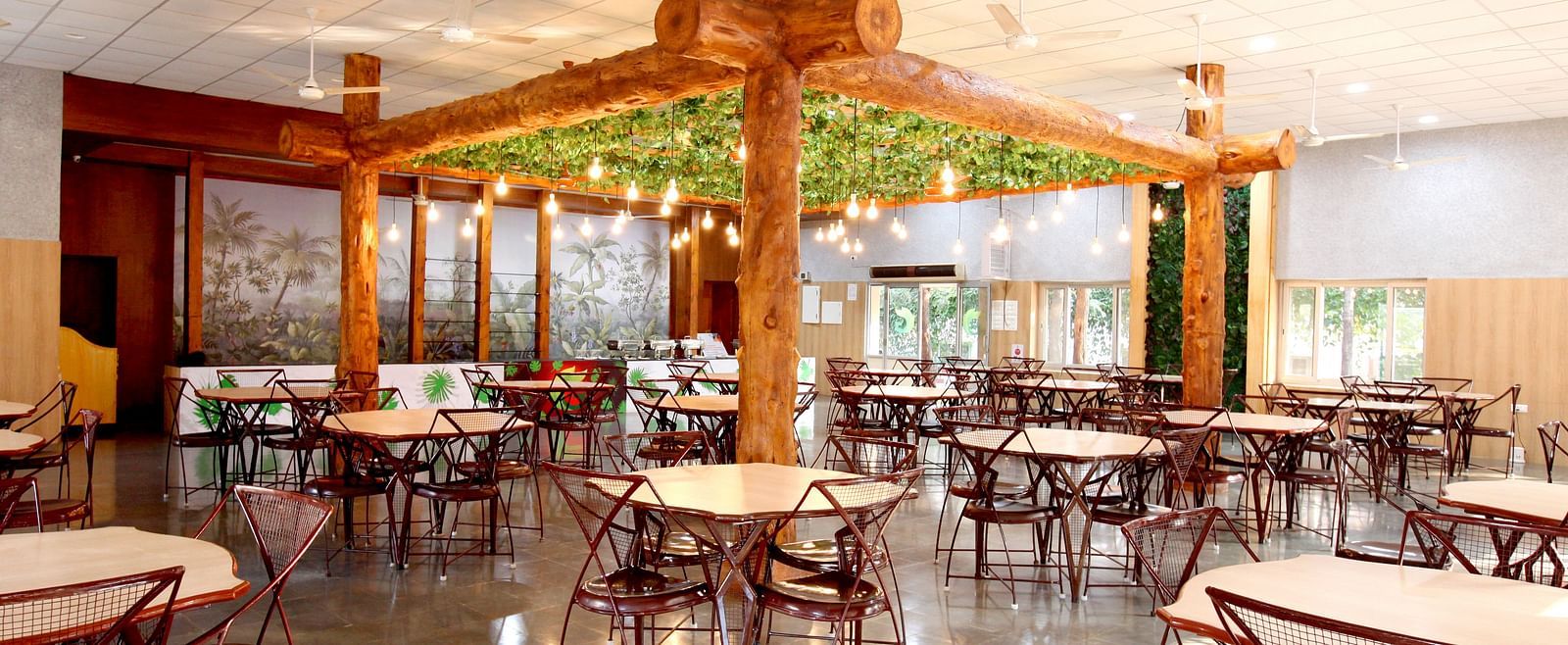 An elaborate seating arrangement at Greens Inn Restaurant featuring wooden furnishing and lit bulbs hanging from the ceiling at Greens Inn - Cozy Dining in Hyderabad.