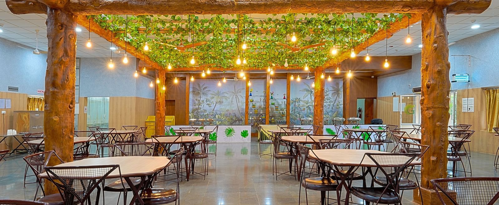 A well-lit restaurant with tables and chairs and light bulbs hanging from the ceiling at Greens Inn - Best Dining Experience in Hyderabad.