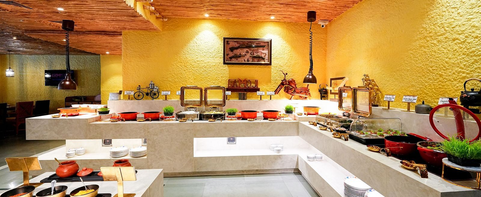 A comprehensive view of a buffet setup in a room with a rustic ceiling and yellow walls. - Tara, Comfort Hotel in Hyderabad - Ramoji Film City.