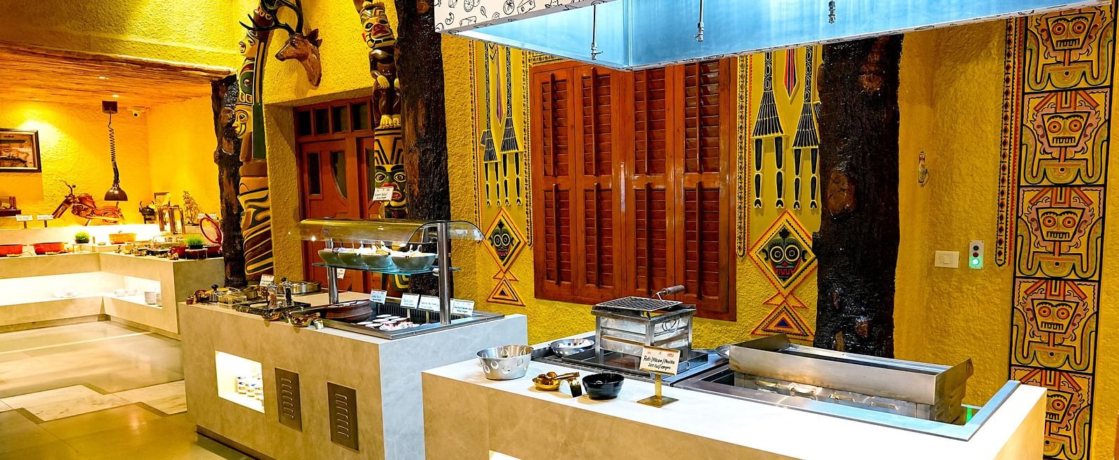 A modern buffet area with sleek service counters and decorative lighting at Tara, Comfort Hotel in Hyderabad - Ramoji Film City.