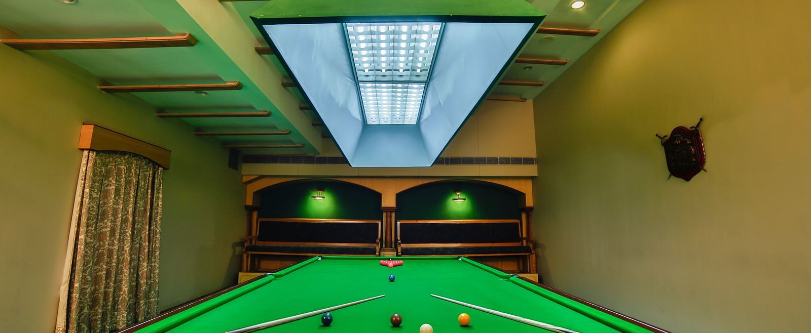 Pool table with billiards cue sticks placed at the corners at Tara, Comfort Hotel in Hyderabad - Ramoji Film City.