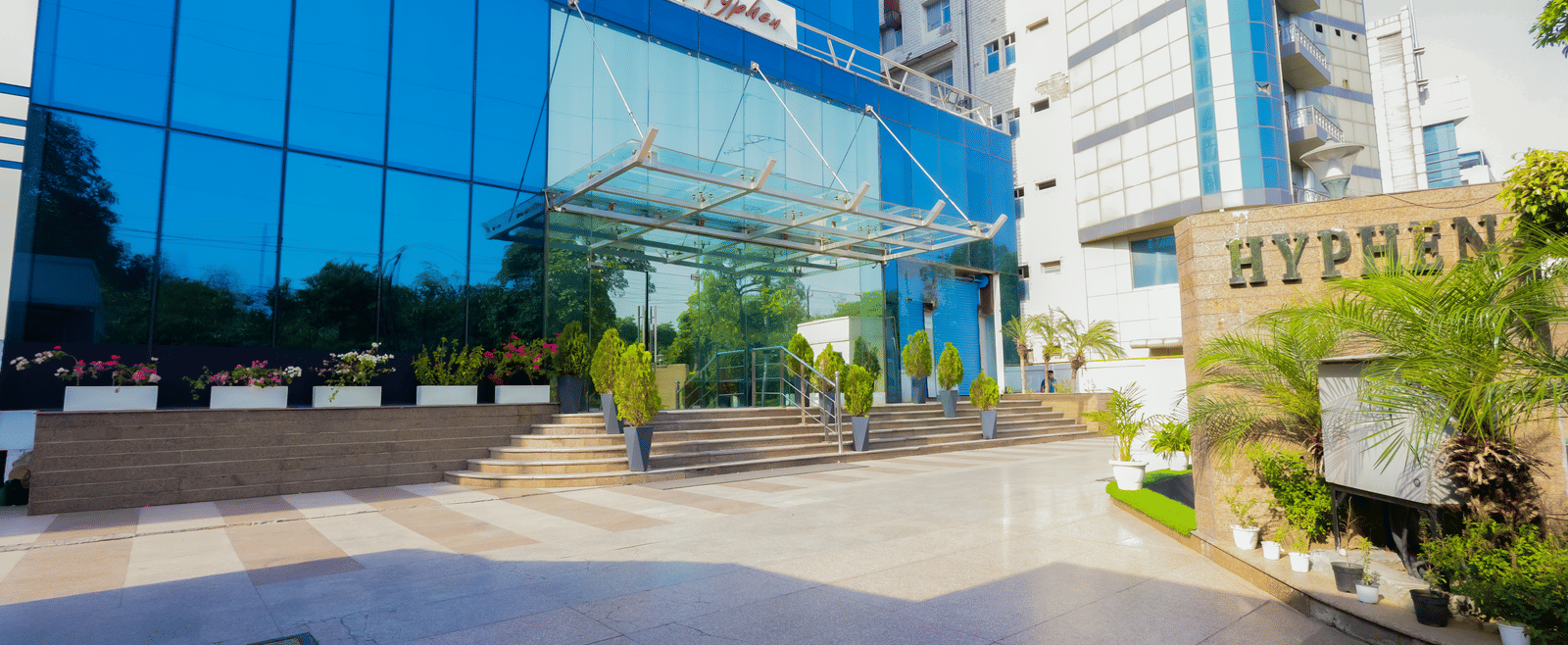 The exterior of a modern building with a glass facade, showcasing the Hyphen Business Hotel signage - Hyphen Business Hotel, Noida