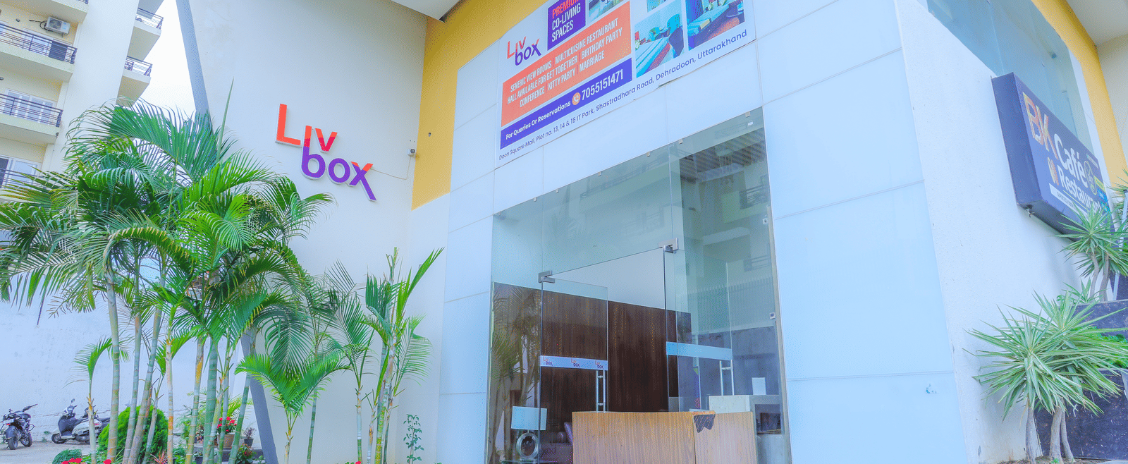 The facade of Livbox, Dehradun, featuring a large entrance, potted plants placed ahead of the entrance.