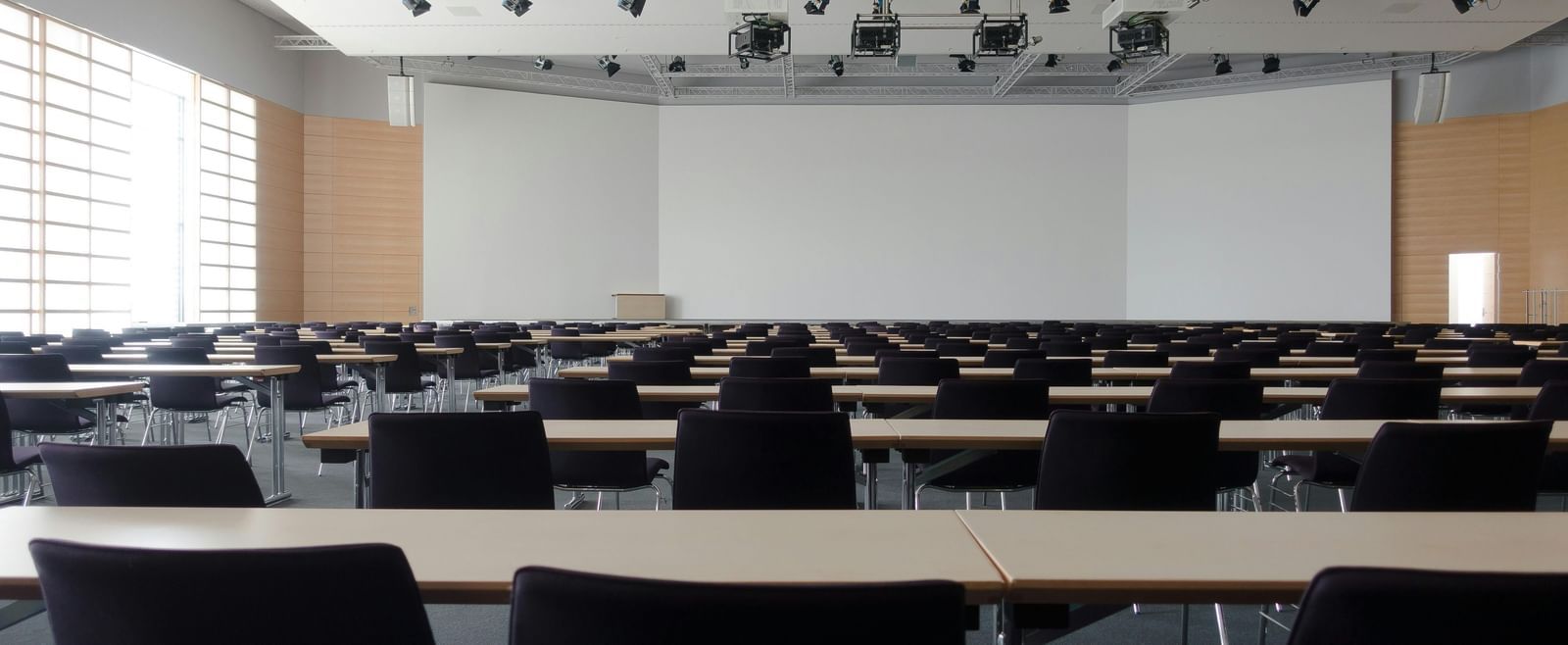 An empty conference room with rows of chairs and a projector screen.