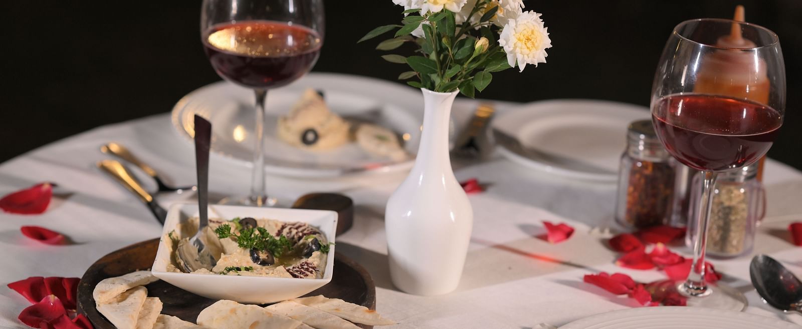 A romantic dinner setup complete with wine and flowers, creating ambience at Royal Comfort Regency.