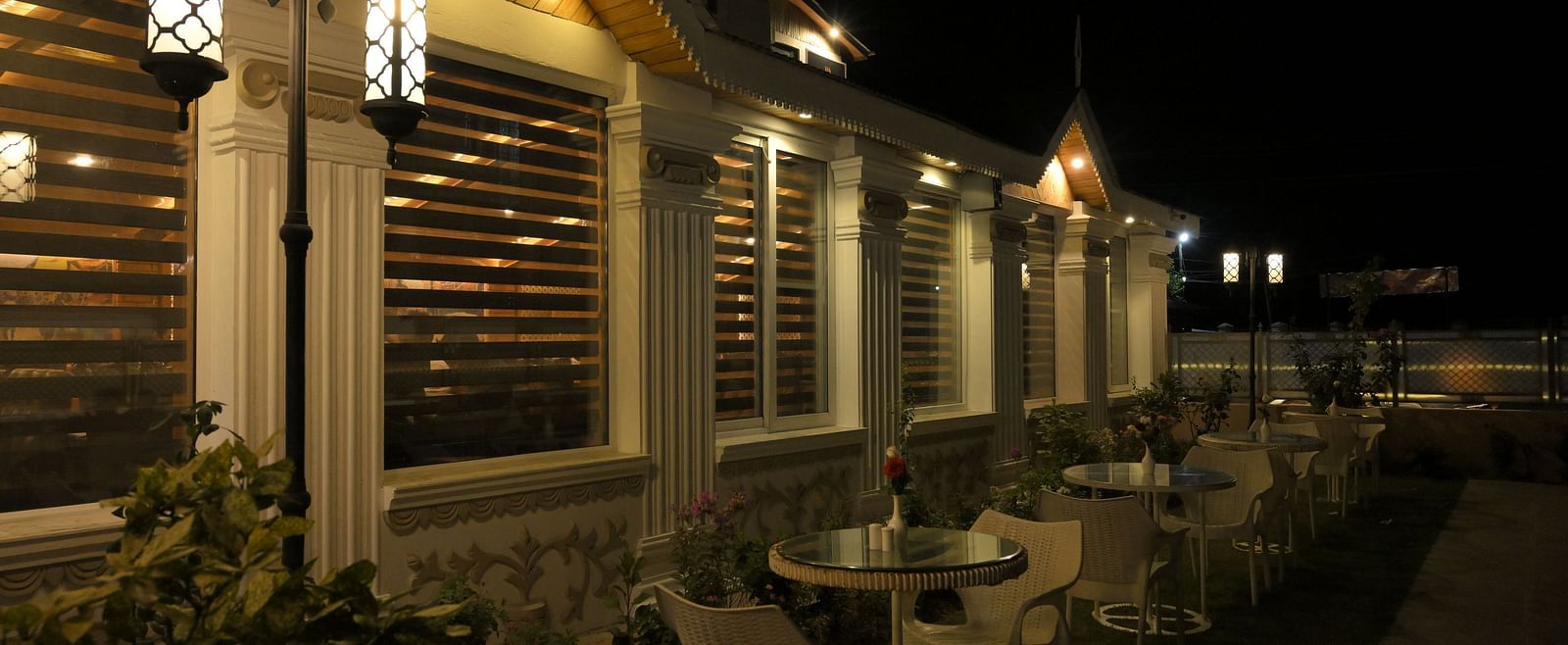 Cosy outdoor seating area at Royal Comfort Regency lit up at night, offering a serene setting for relaxed evening dining.