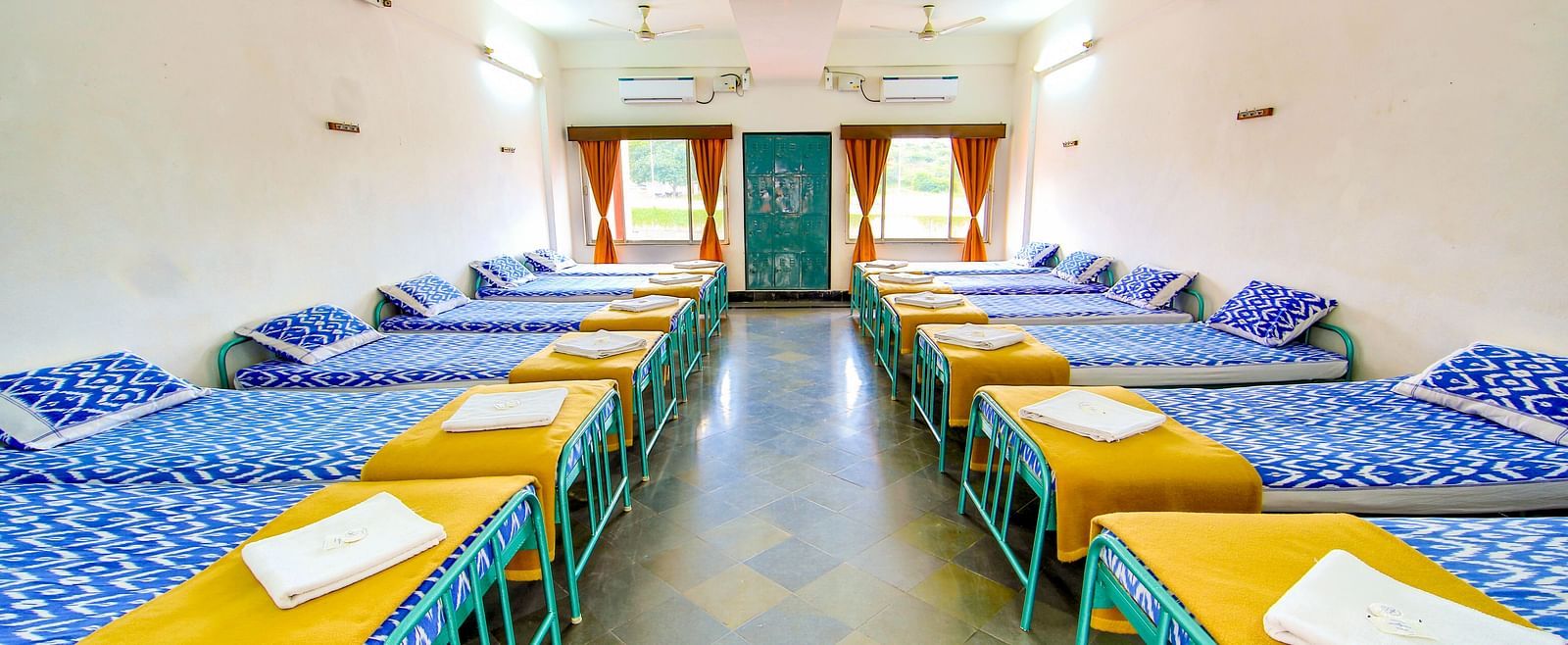 A dormitory with pillows and blankets on each bed at Sahara - Cozy Dormitories in Hyderabad.