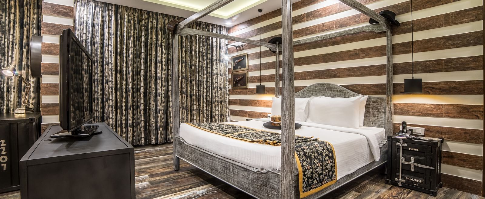 An opulent hotel room with a four-poster bed, striped walls, and dark wood furniture creating a luxurious atmosphere A grand hotel suite with an opulent red and white decor, large bed, and seating area, reflecting a traditional style at Sitara Luxury Hotel